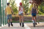 Group Of Friends With Roller Skates And Bike Riding In The Park Stock Photo