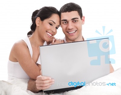 Couple Sitting In Bed With Laptop Stock Photo