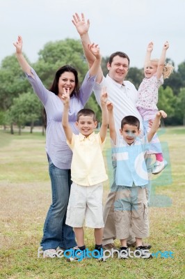 Happy Family On Outdoors  Enjoying By Raising Hands Stock Photo
