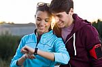 Portrait Of Young Couple Using They Smartwatch After Running Stock Photo