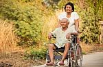 Senior Woman Pushing Her Disabled Husband On Wheelchair Stock Photo