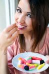 Cute Young Woman Eating Jelly Candies With A Fresh Smile Stock Photo