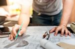 Close-up Of Person's Hand Drawing Plan On Blue Print With Archit Stock Photo