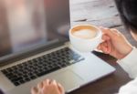 Hand On Cup Of Coffee At Work Table Stock Photo