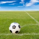 Soccer Ball On Soccer Field Against Blue Sky Stock Photo