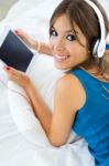 Beautiful Girl Listening To Music With Tablet On Sofa At Home Stock Photo