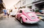 Blurred Pink Car On The Road With People Stock Photo