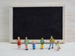 Miniature Children Standing In Front Of A Blackboard On Wooden B Stock Photo