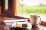 Cake And Cup Of Coffee On Wooden Table Near Window Sill. Time With Snacks Concept Stock Photo