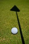 A Golf Ball And The Shadow Of The Hole Flag Stock Photo