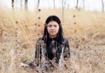 Asian Woman Meditating In Grass Field  Stock Photo