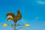 A Cockerel Wind Vane Against Blue Sky Stock Photo