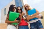 Three Girls Chatting With Their Smartphones At The Campus Stock Photo