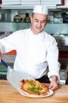 Chef Placing Pizza, Ready To Be Served Stock Photo