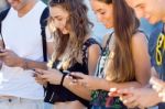 A Group Of Students Having Fun With Smartphones After Class Stock Photo