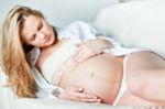 Young Pregnant Woman Resting On Sofa Stock Photo