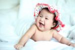 Newborn Baby With Colorful Floppy Hat Lying Down On A White Blan Stock Photo