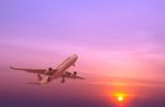 Commercial Airplane Flying At Sunset Stock Photo