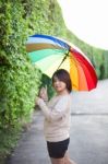 Asian Woman Holding An Umbrella On The Sidewalk Stock Photo