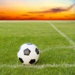 Soccer Ball On Soccer Field Against Sunset Sky Stock Photo