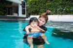 The Kid And Mom Play Together In The Pool Stock Photo