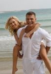 Couple Piggyback Ride At Beach Stock Photo