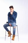 Male Model In Denim Jeans Sitting On A Chair . Studio Shoot Stock Photo