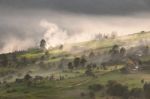 Alpine Village In Mountains. Smoke, Bonfire And Haze Over Hills Stock Photo