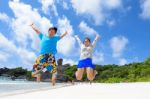 Father And Daughter Jumping On Beach At Thailand Stock Photo