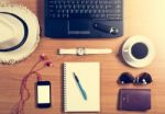 Office Desk With Computer, Supplies, Coffee Cup, Passport, Sungl Stock Photo