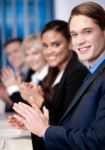 Corporate Team Sitting In A Row And Applauding Stock Photo