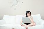 Girl On White Sofa With Laptop Stock Photo