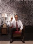 Young Man In White Shirt Sitting On Red Sofa Stock Photo