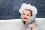 Little Girl Sitting In A Bath With Soap Suds Stock Photo