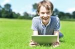 Young Boy With Tablet Device At Grassland Stock Photo