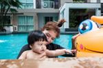 The Kid And Mom Play Together In The Pool Stock Photo