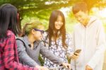 Group Of Asian Teenager Walking In The Park And Enjoyed Watching Video From Smartphone  Stock Photo