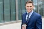 Smiling Businessman With Coffee Sipper Stock Photo