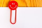 Close Up Of A  Red Paper Clip And White Paper On Wood Table Stock Photo