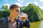 Young Man In Sunglasses Is Drinking Beer In The Park Stock Photo