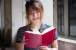 Portrait Of Thai Adult Beautiful Girl Reading Red Book Stock Photo