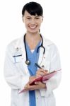 Friendly Doctor Updating Medical Record Of A Patient Stock Photo