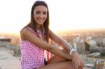 Pretty Girl Sitting On The Roof At Sunset Stock Photo