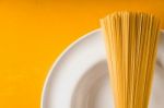 Raw Spaghetti  On The White Plate On The Yellow Background Stock Photo