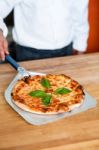 Chef Picking Up Pizza From The Base Stock Photo