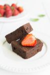 Chocolate Brownie Cake On White Plate Decorated With Strawberrie Stock Photo