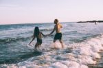 A Couple Is Running On Beach While The Sun Is Set Stock Photo