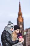 Young Couple In Love Embracing And Drinking Hot Drink From Red C Stock Photo