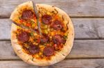 Delicious Baked Salami Pizza Served On Rustic Wooden Table Stock Photo