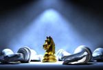 Golden Chess Knight Standing At The Center Of Spotlight Among White Chess Knight Falling Down, Business Success And Leadership Concept Stock Photo